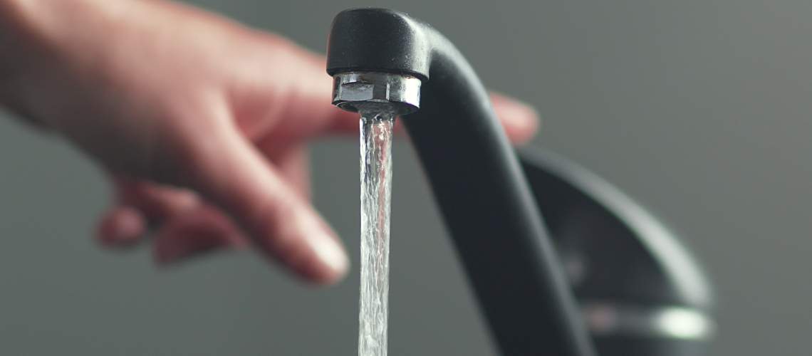 A person turns off a running faucet.
