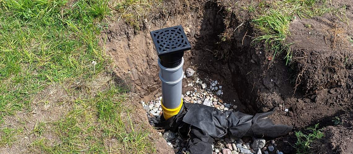 Overflow and infiltration well connected to drainage pipes, buried in a pit covered with stones.