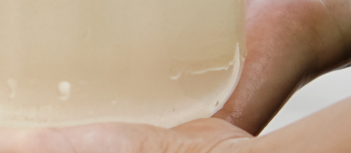 A child's hands holds transparent jar of water at lake.