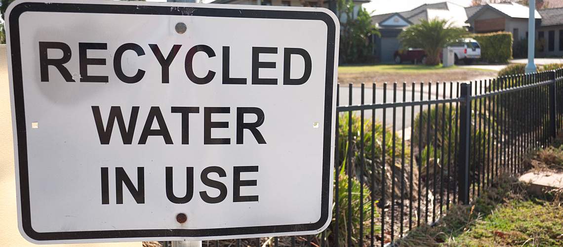 "Recycled Water in Use" sign near lawn.
