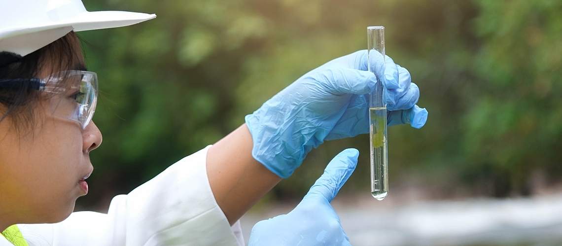 An environmentalist collects river water quality samples.
