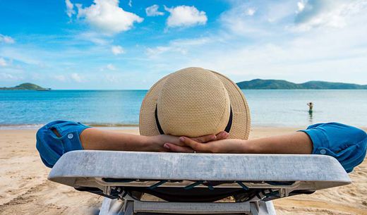 Person lounges on a beach chair.