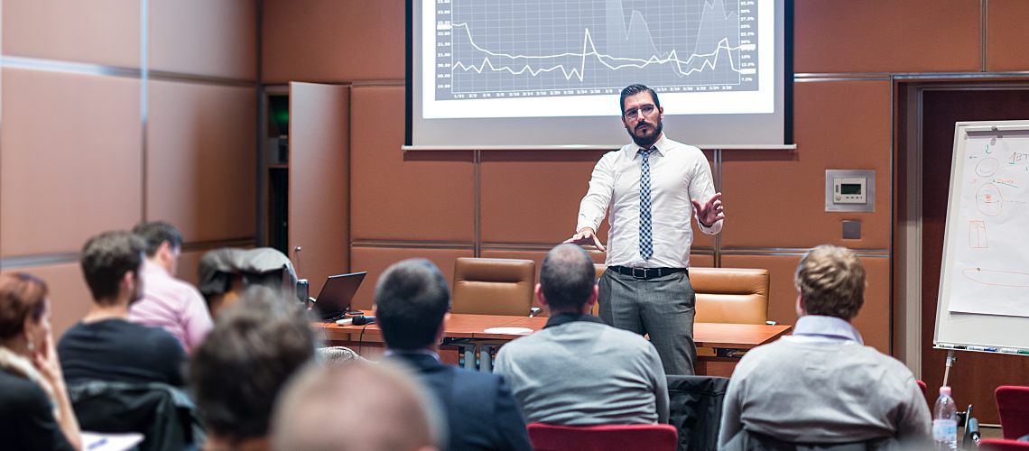 Man presenting data to a full room.