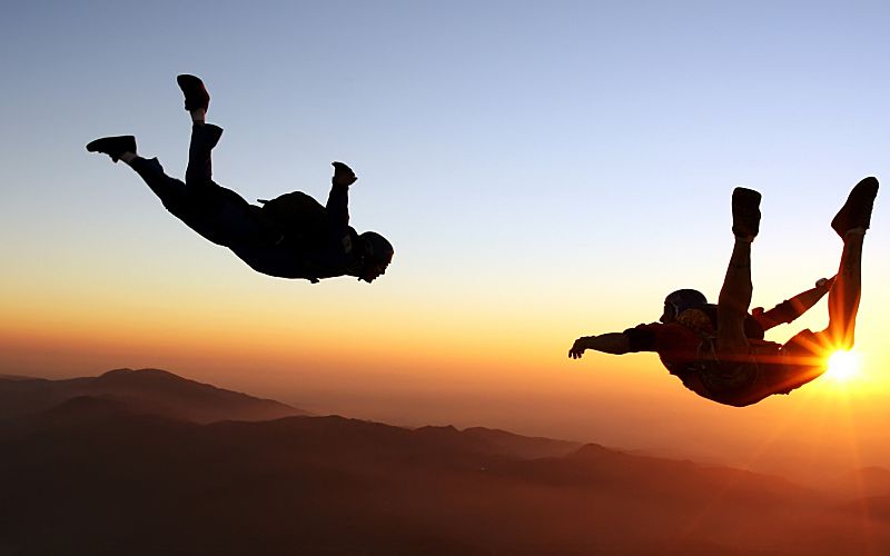 Two people skydiving during sunset.