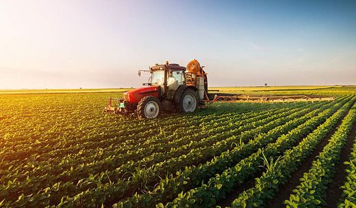 A tractor spraying a soybean field with chemicals.