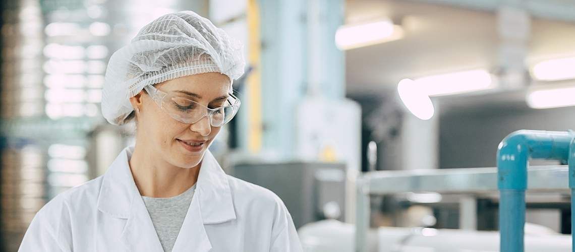 A woman wearing a plastic scrub cap stands in a water laboratory.