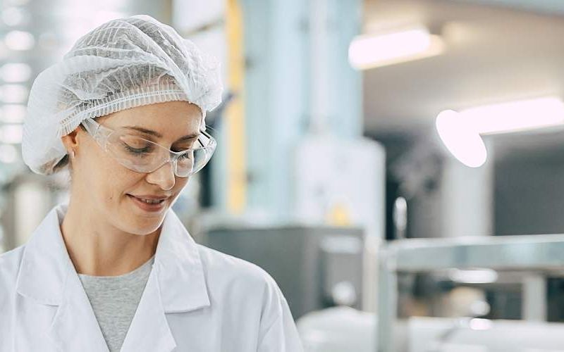 A woman wearing a plastic scrub cap stands in a water laboratory.