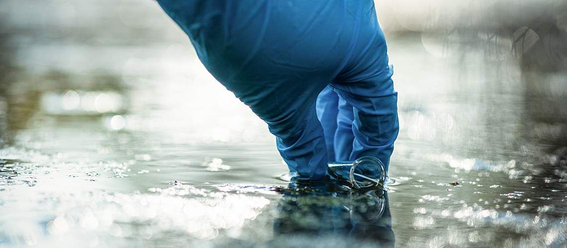 A person collects a water sample.