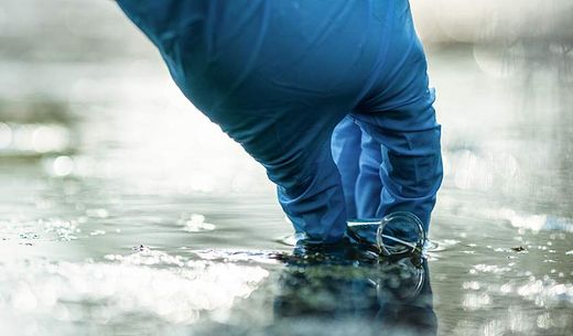 A person collects a water sample.