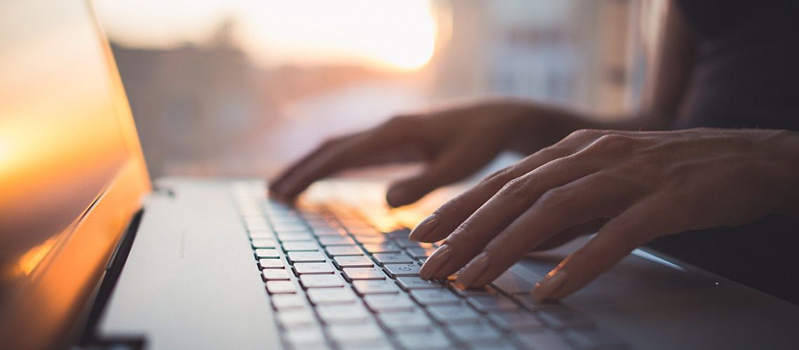 Woman typing on laptop sitting at desk.