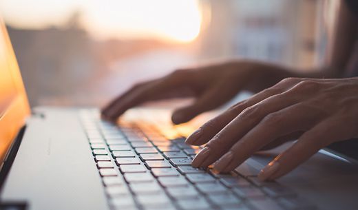 Woman typing on laptop sitting at desk.