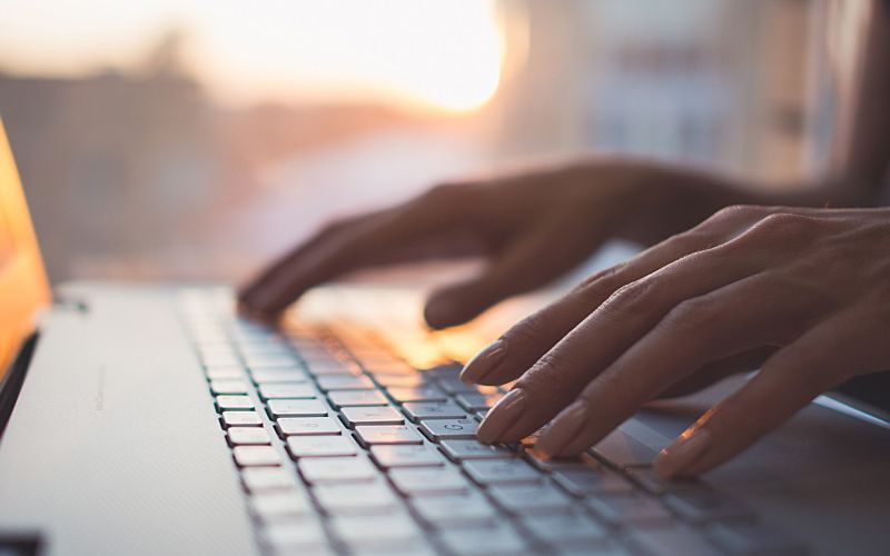 Woman typing on laptop sitting at desk.