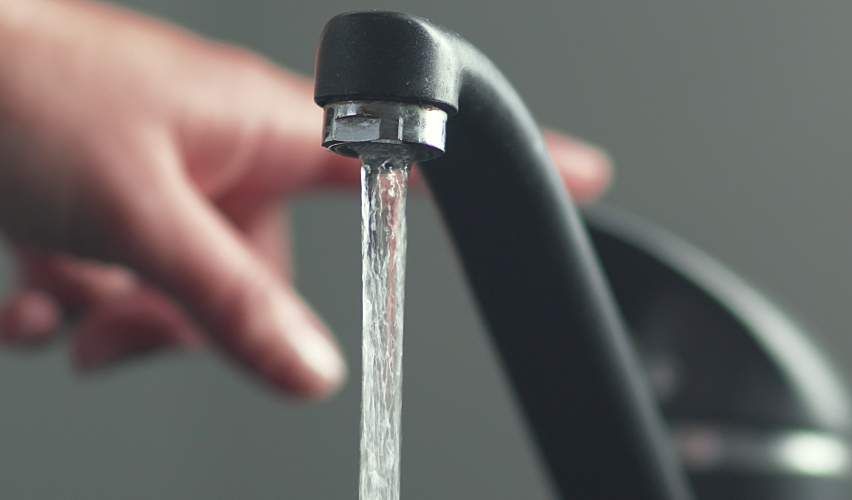 A person turns off a running faucet.
