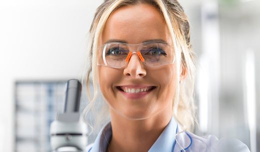 Young, happy laboratory technicians wearing safety glasses.