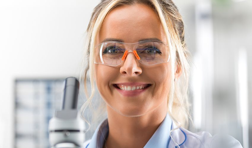 Young, happy laboratory technicians wearing safety glasses.
