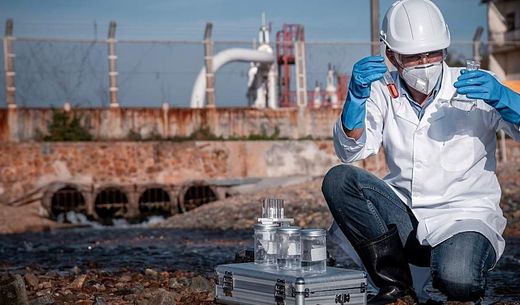 Scientist tests for water pollution at an industrial site.