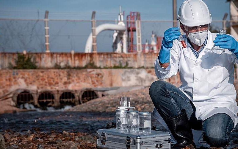 Scientist tests for water pollution at an industrial site.