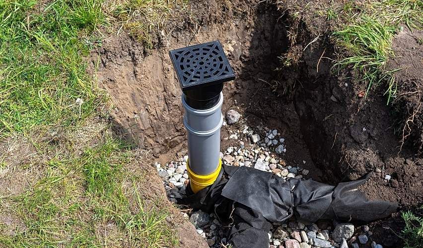 Overflow and infiltration well connected to drainage pipes, buried in a pit covered with stones.