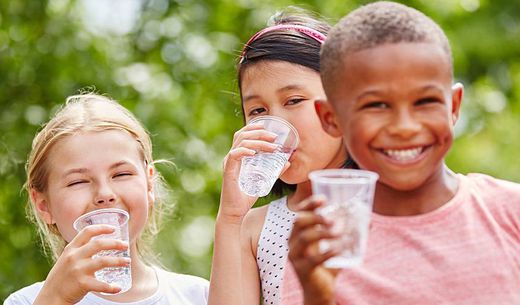 Group of children drinking water from cups.