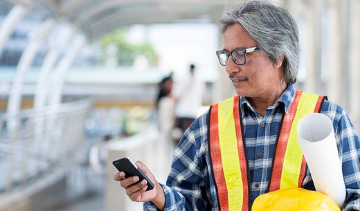 Construction worker looks at his cell phone.