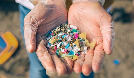 Person holds microplastics of different shapes and sizes in their hands.