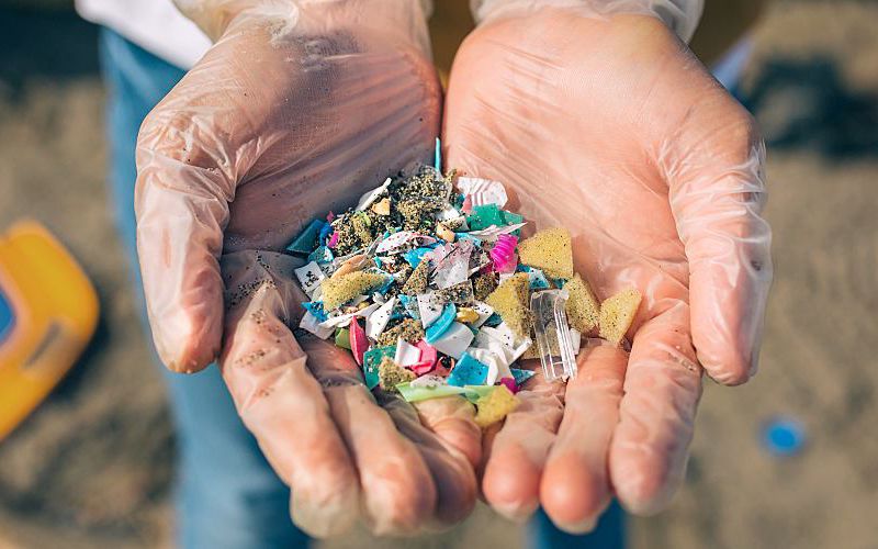 Person holds microplastics of different shapes and sizes in their hands.