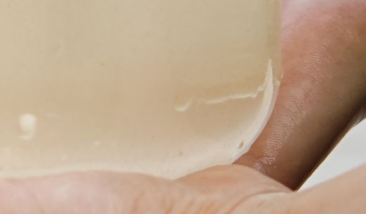 A child's hands holds transparent jar of water at lake.