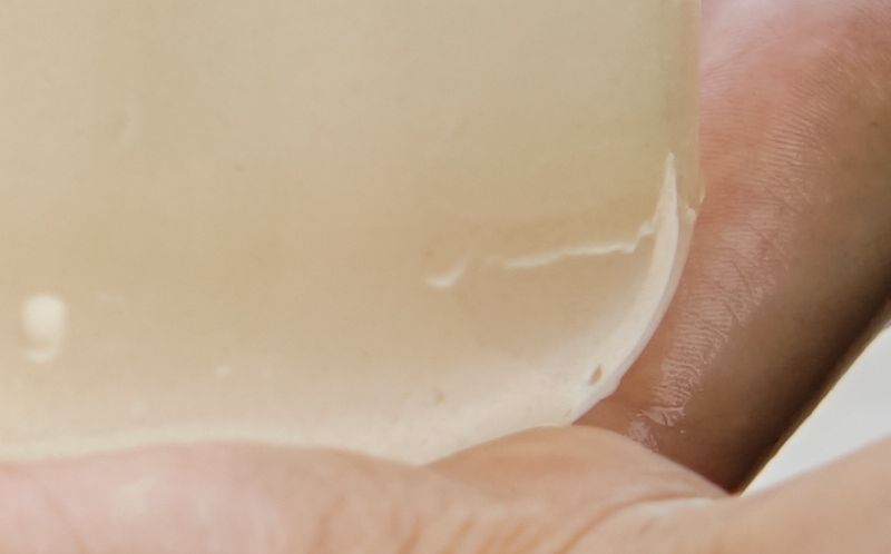 A child's hands holds transparent jar of water at lake.