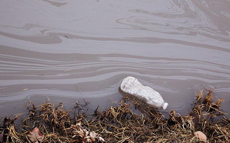 Floating water bottle in a polluted stream