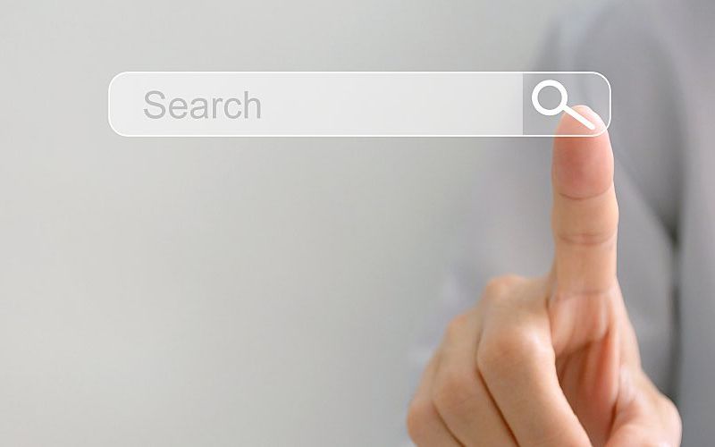 A person taps a search icon with their finger.