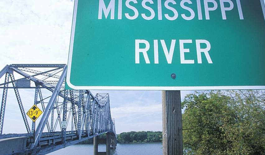 Mississippi River sign in front of a truss bridge over a stretch of river