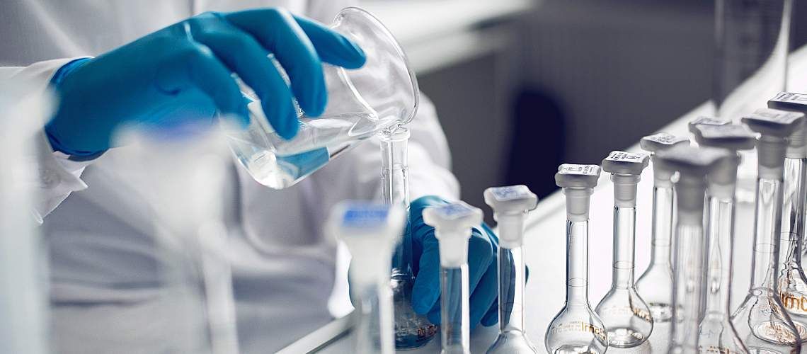A gloved chemist works with samples in a lab.