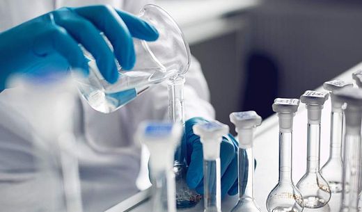 A gloved chemist works with samples in a lab.