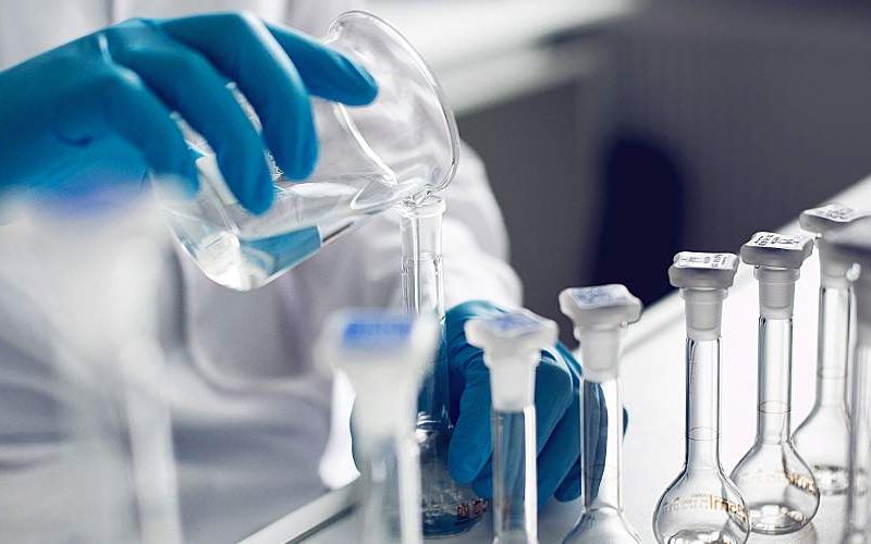 A gloved chemist works with samples in a lab.