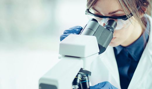 Water laboratory employee looking through a microscope.