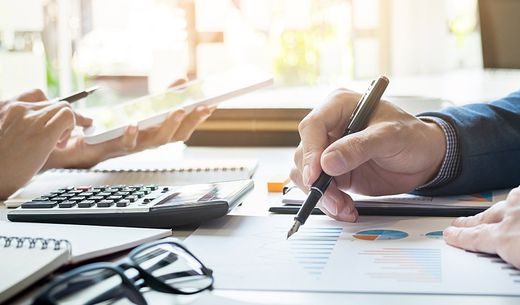 Two employees sitting at a work table working on company budget.