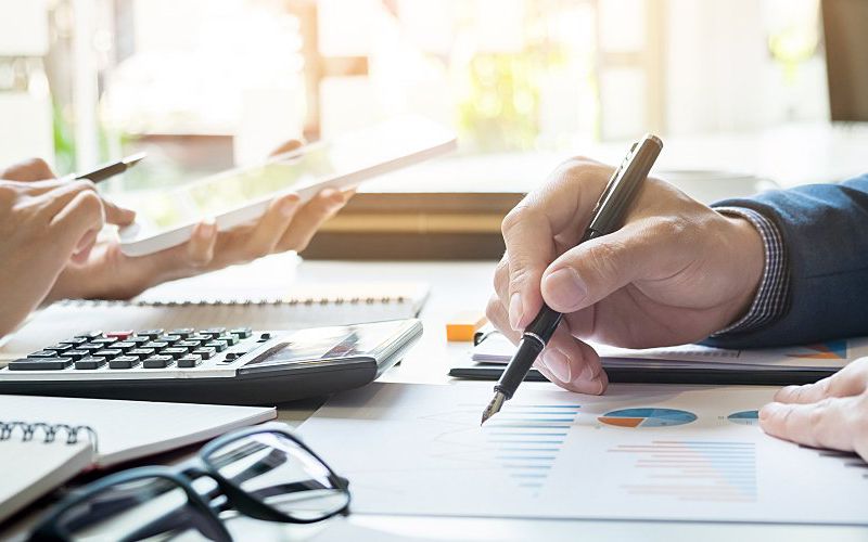 Two employees sitting at a work table working on company budget.