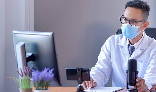 Lab employee wearing a mask at a computer.