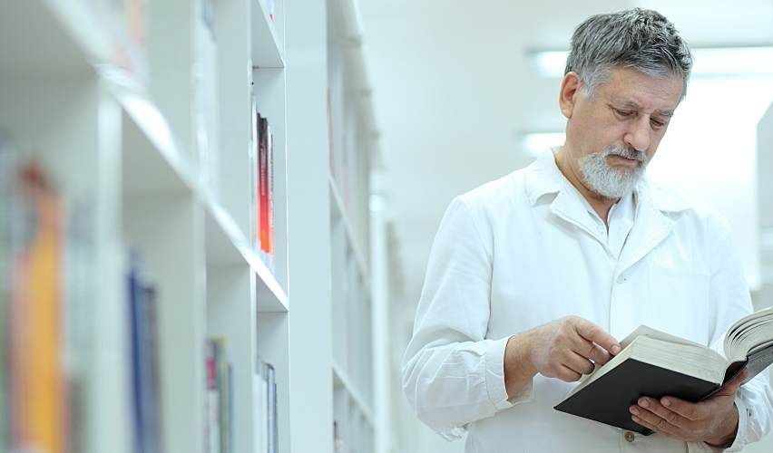 Water laboratory employee checking a reference in a book in the laboratory library.