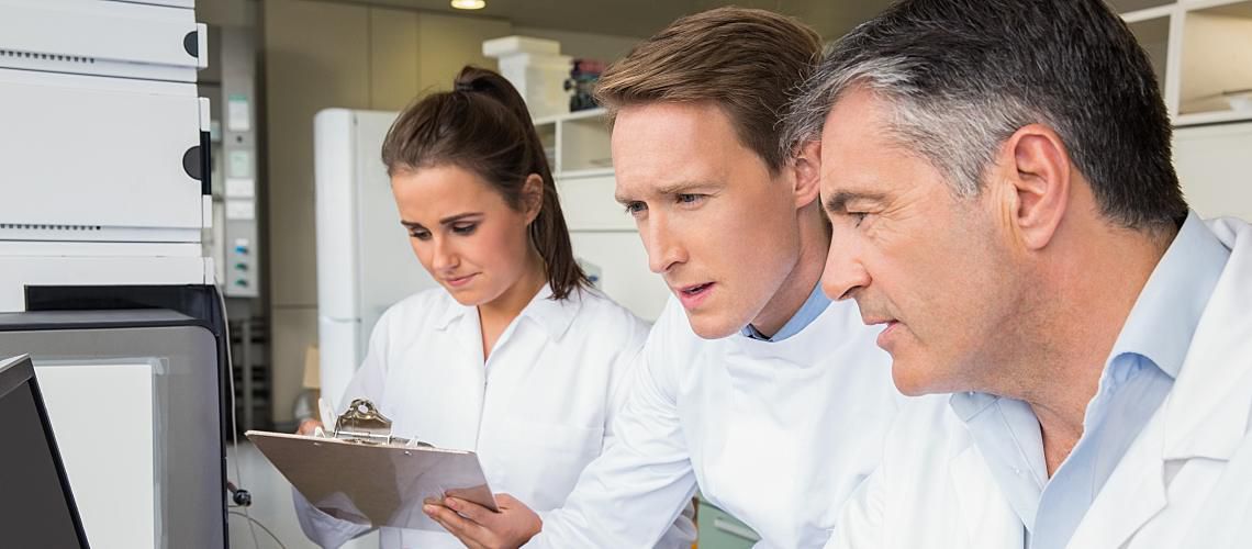 Three employees in lab coats working in a lab.
