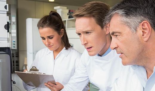 Three employees in lab coats working in a lab.