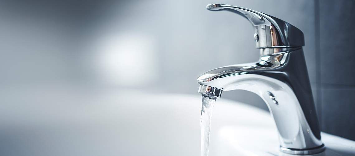 A bathroom tap with flowing water.