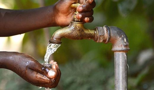 An African child turns on an outdoor tap.