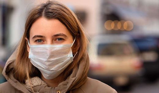 Woman wearing a mask in a city.