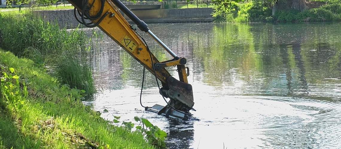A heavy-duty excavator dredging a river bottom.