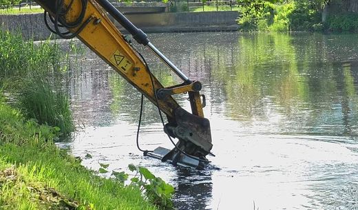 A heavy-duty excavator dredging a river bottom.