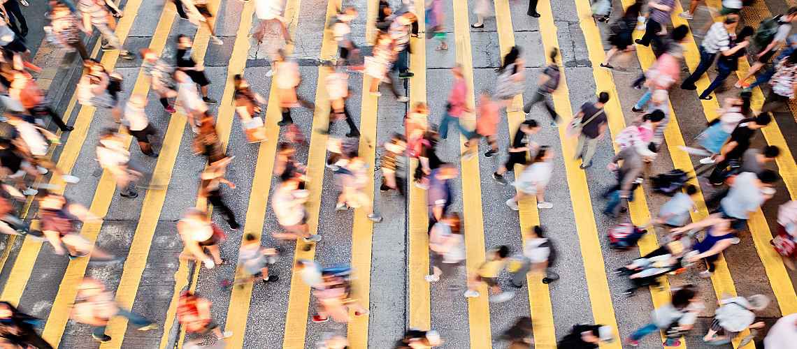 Large crowd of people crossing a busy street.