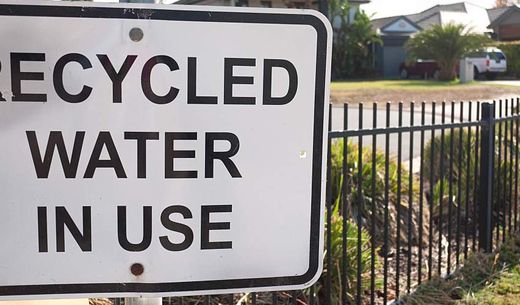 "Recycled Water in Use" sign near lawn.