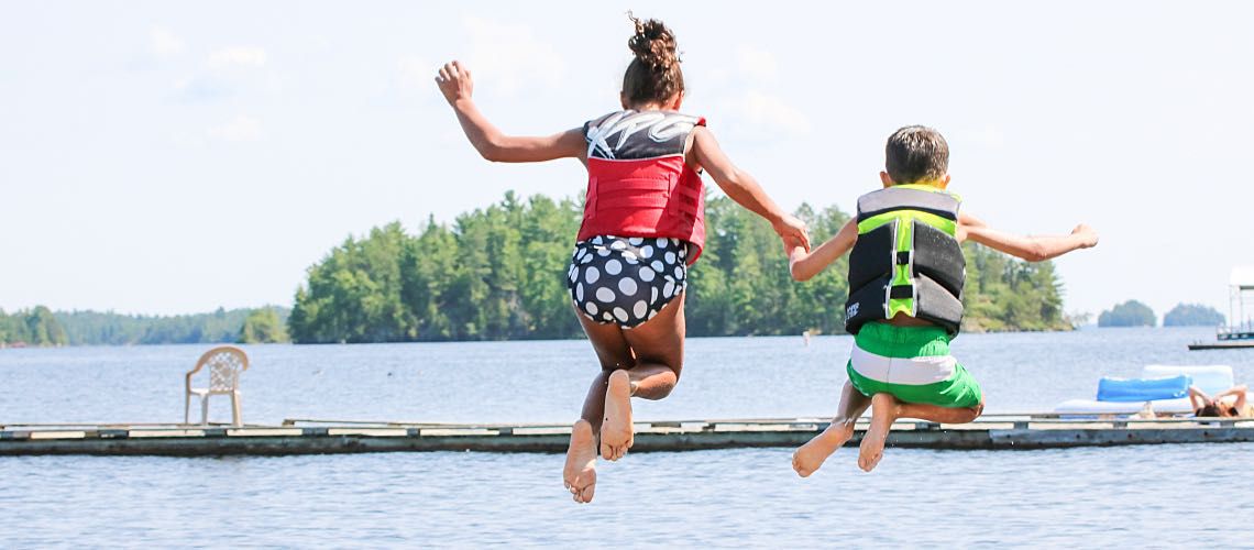 Two children jump into a lake for fun.