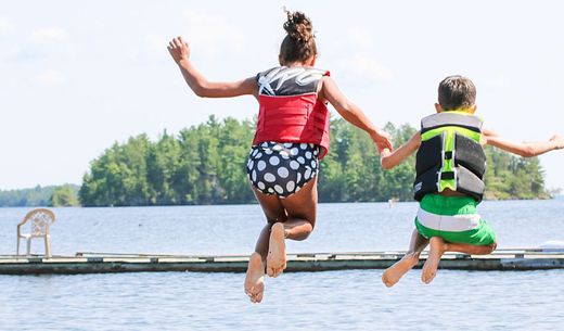 Two children jump into a lake for fun.